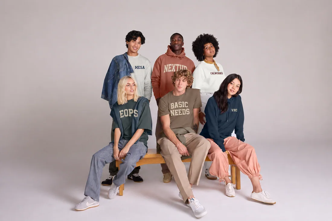 Six students on a bench in college-program sweatshirts, tees and hoodies